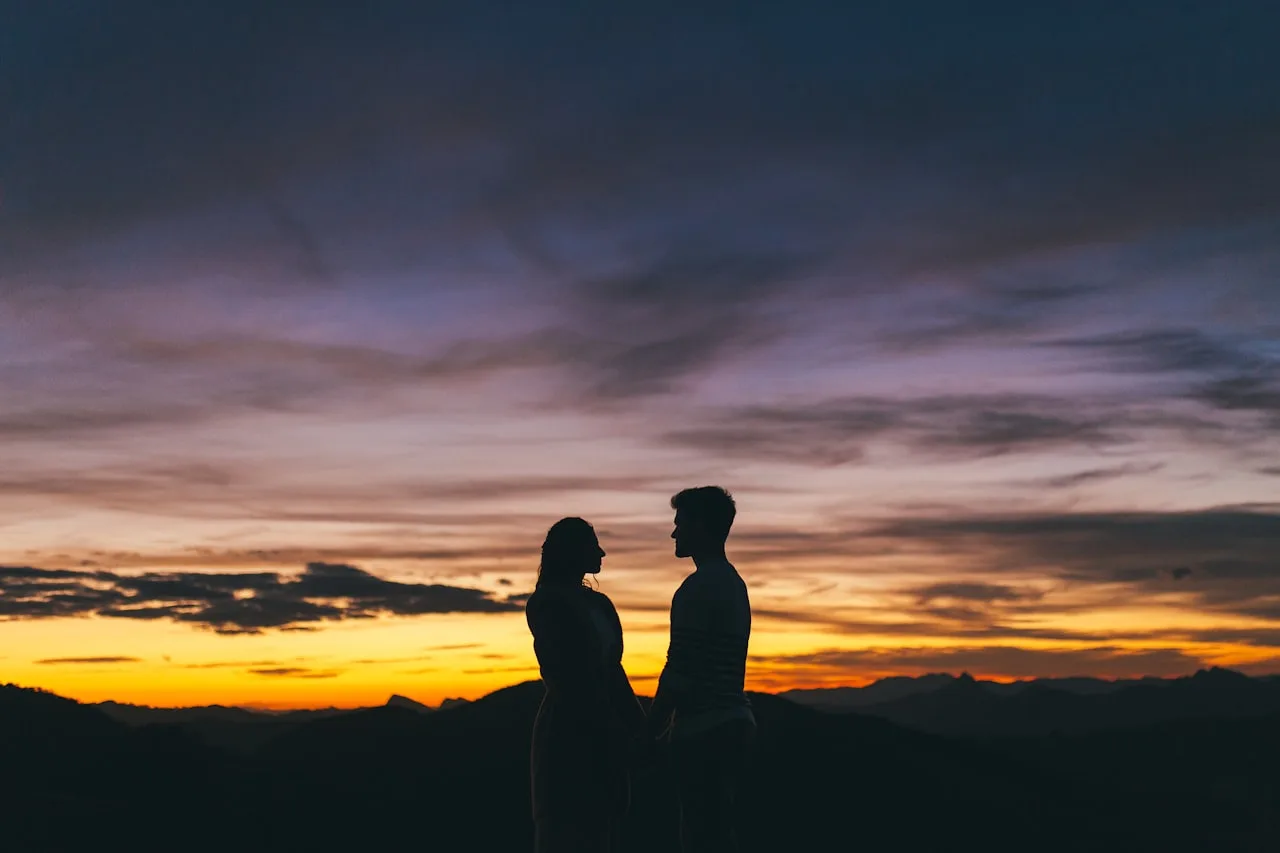 Couple de randonneurs admirant un coucher de soleil sur les sommets