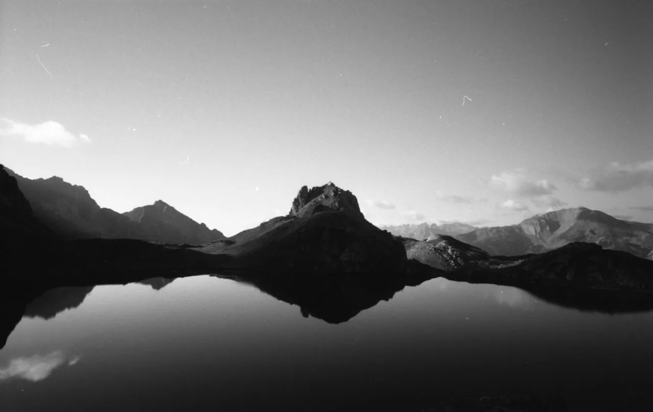 Lac d’altitude des Alpes reflétant les sommets au lever du jour